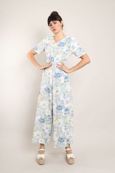 FEATURES - 1990s jumpsuit - White, periwinkle, blue, green colors - Muted floral print - Short sleeves - V-neckline - Slightly fitted waist - Flowing wide leg pants - Zips up the back CONDITION Good vintage condition: super faint discoloration along the front of the neckline; very edge of the bottom hem of the pants has some light dirt-like markings. MEASUREMENTS & FIT suggested letter size: S/M shoulder: 14.5" bust (underarm): 35"-36" waist: 31" hip: 44" length: 58" inseam: 26.5" shoulder to crotch: 31" sleeve: 10" color: white, periwinkle, blue, green material: feels like rayon, zipper label: no label pinned on model? no Note on fit: Adrianne is 5'10 33-25-36 with a modern dress size 2-4, letter size XS/S and a size 26 in jeans. All items are measured while the garment is laying flat. Th Floral Print Jumpsuits And Rompers For Garden Party, Vintage Floral Print Jumpsuit For Spring, Vintage Floral Print Jumpsuits And Rompers, Casual Floral Print Maxi Jumpsuits And Rompers, Blue Floral Print Short Sleeve Jumpsuit, Floral Print Jumpsuits For Garden Party In Spring, Floral Print Jumpsuit For Spring Garden Party, Fitted Floral Print Jumpsuits For Garden Party, Fitted Floral Print Maxi Jumpsuits And Rompers