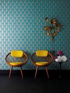 two chairs sitting next to each other in front of a blue wall