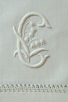 an embroidered monogram with the word love and flowers in white on a light gray background