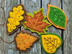 four autumn leaf ornaments on a wooden surface