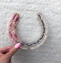 a hand holding a pink and white object on top of a carpeted floor next to a pair of scissors