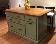 a kitchen island with two stools next to it and a potted plant on top