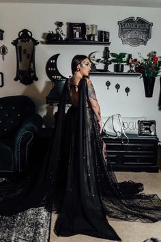 a woman standing in a room wearing a black dress with sheer fabric on the skirt