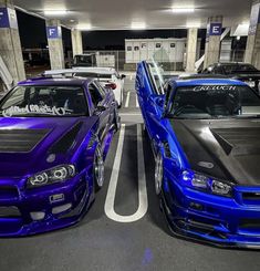 two blue cars parked next to each other in a parking garage