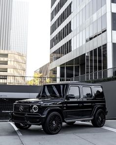 a black mercedes g - class parked in front of a tall building