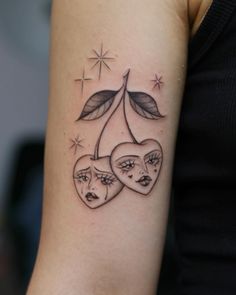 two hearts with leaves and faces tattoo on the arm