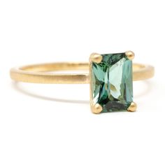 a gold ring with an emerald colored stone