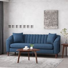 a living room with a blue couch and two tables in front of the window,