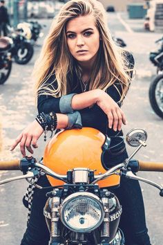 a woman sitting on the back of a motorcycle with her hand on the handlebars