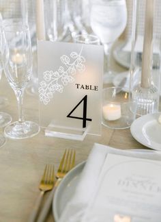 the table numbers are displayed with candles and place cards for guests to sit down at