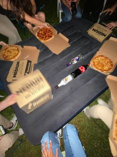 people sitting around a table with pizzas in boxes on it