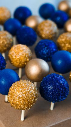 blue and gold cake pops with sprinkles are on a brown tablecloth