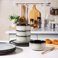 there are plates and croissants on the kitchen counter with utensils