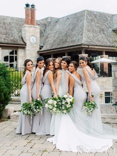 a group of women standing next to each other in front of a building with a clock on it