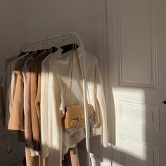 a rack with sweaters and handbags hanging from it's hooks in front of a door