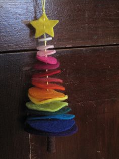 a rainbow christmas tree hanging from a wooden door with a star on it's top