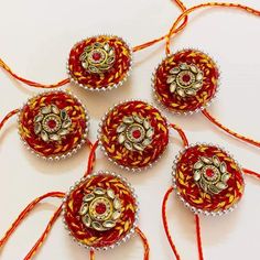 four red and yellow beaded ornaments on a white surface with orange string around them