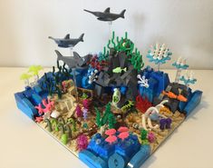 an ocean scene made out of legos on a white table with dolphins and other sea creatures