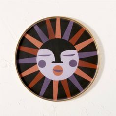 a black and orange plate with a face painted on it's side, against a white wall