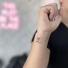 a woman's arm with a small anchor tattoo on her left wrist and the word love written across it