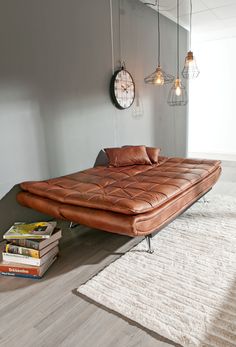 a brown leather futon bed sitting on top of a wooden floor next to a white rug