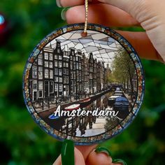 a hand holding a glass ornament with the words amsterdam on it