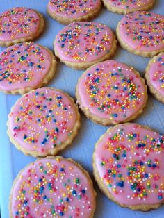 pink frosted cookies with sprinkles on a blue tray