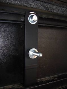 a close up of a metal door handle on a black cabinet with silver knobs