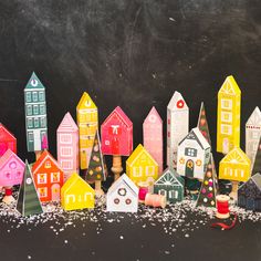 a group of colorful wooden houses sitting on top of a black surface with sprinkles