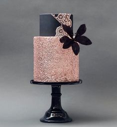 a three tiered cake with pink and black frosting