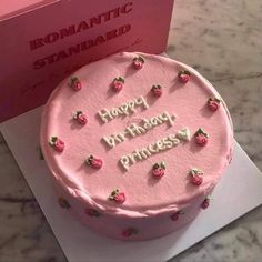 a pink birthday cake sitting on top of a table