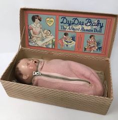 a doll in a box with an ad for diapers on the lid and inside