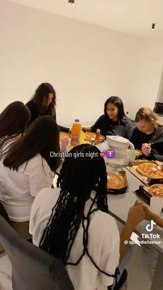 a group of people sitting around a table eating pizza