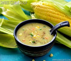 a bowl of soup with corn on the cob in it and an ear of corn next to it