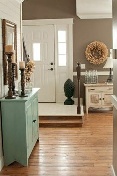 an entryway with wooden floors and white walls, decorated with wreaths on the door