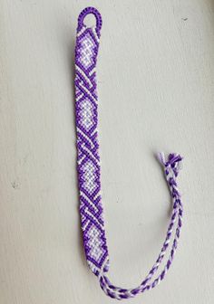 a purple and white beaded object sitting on top of a table