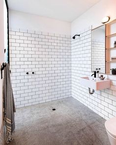 a white tiled bathroom with two sinks and a toilet