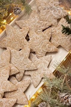 christmas cookies are arranged on a tray next to pine branches