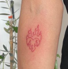 a small red tattoo on the arm of a woman's left leg, with flames coming out of it