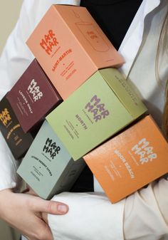 a woman is holding six boxes of different flavored chocolates in her hands, all stacked on top of each other