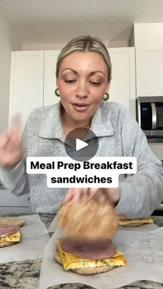 a woman is making sandwiches in the kitchen with her hands and fingers out to eat them