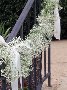 flowers are tied to the iron railings by ribbons on each side, along with baby's breath