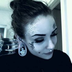 a woman with white makeup and snowflakes on her face