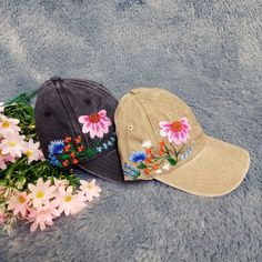 two hats sitting next to each other on top of a blue blanket with flowers around them