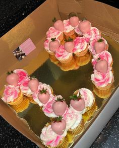 cupcakes with pink frosting and strawberries on top in a box