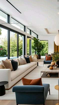 a living room filled with lots of furniture and large windows overlooking the trees in the backyard