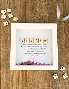 a scrabble frame sitting on top of a wooden table with letters spelling sister