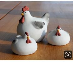 three ceramic chickens sitting on top of a wooden table