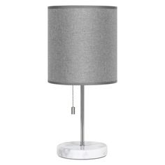 a white table lamp with a grey shade on the base and a gold chain around it