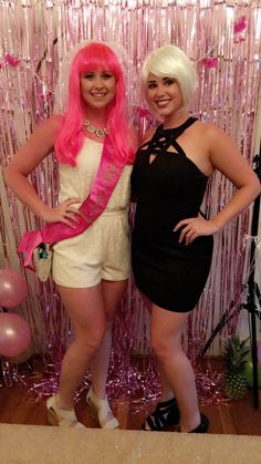 two women standing next to each other in front of a pink wall with streamers